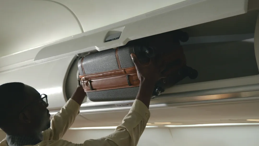 man putting his luggage on a plane